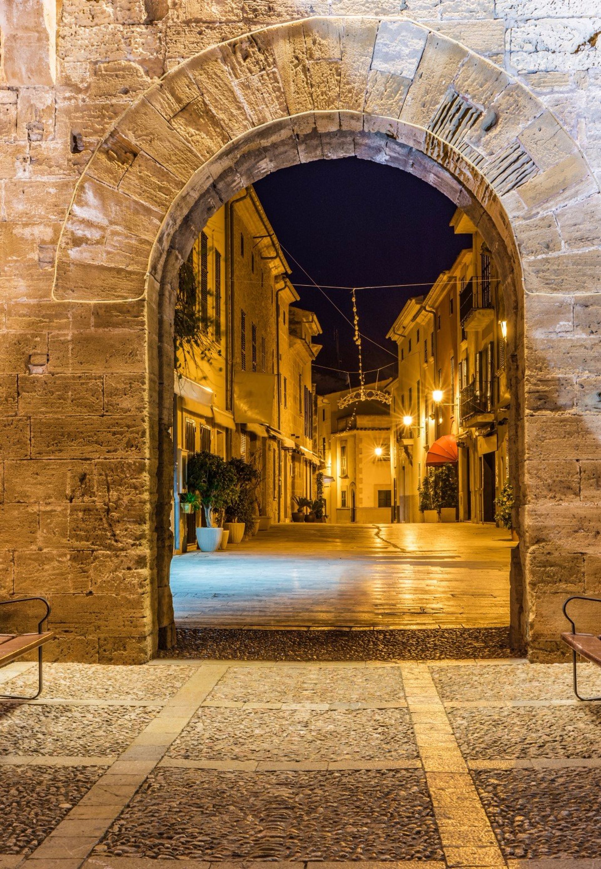 Alcudia Old Town at night, seen through a medieval gate