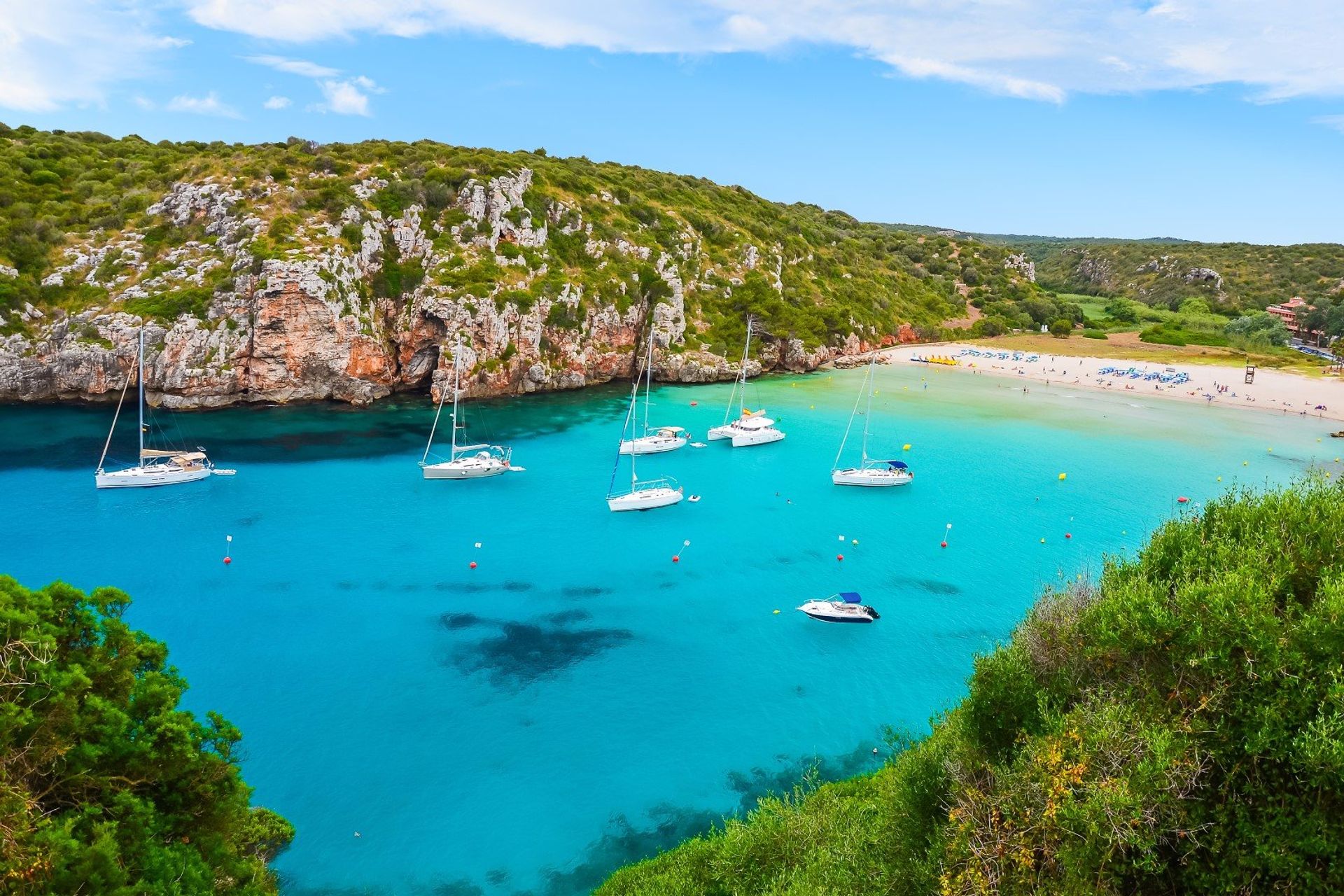 Moored yachts on the beautiful turquoise waters of Cala en Porter in south east Menorca