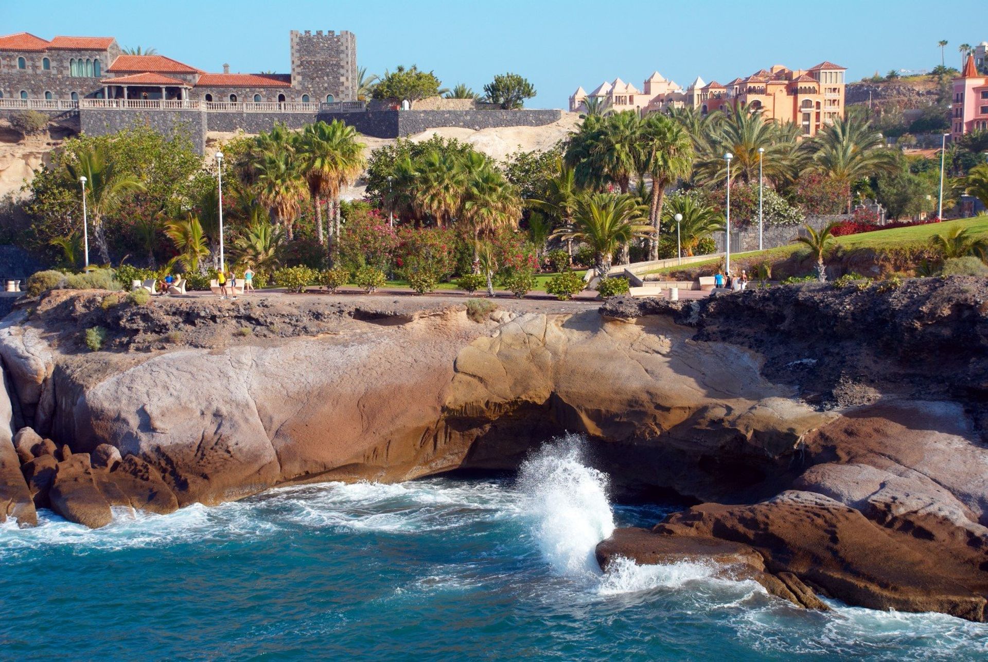 Waves crashing against volcanic rocks at Playa de las Americas bay