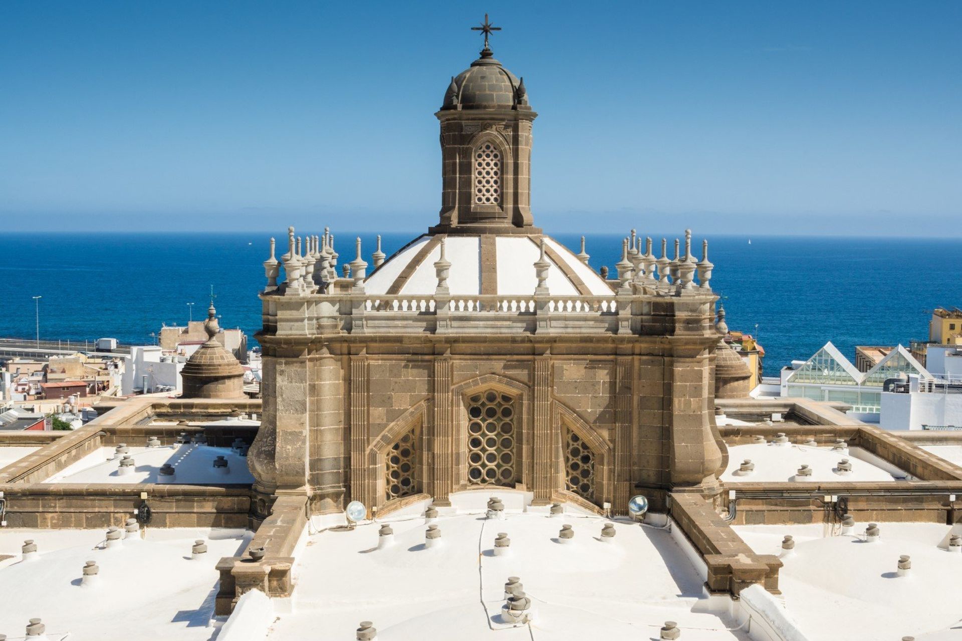 The white dome of Santa Ana Cathedral against the blue Atlantic Ocean in Las Palmas
