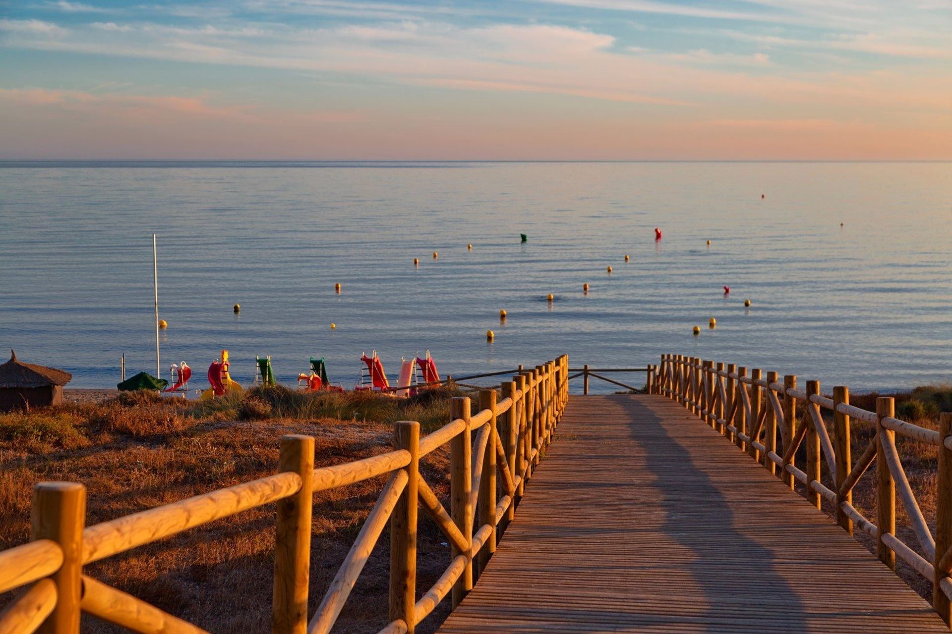 Wooden path on the beach of Mijas Costa resort at sunset