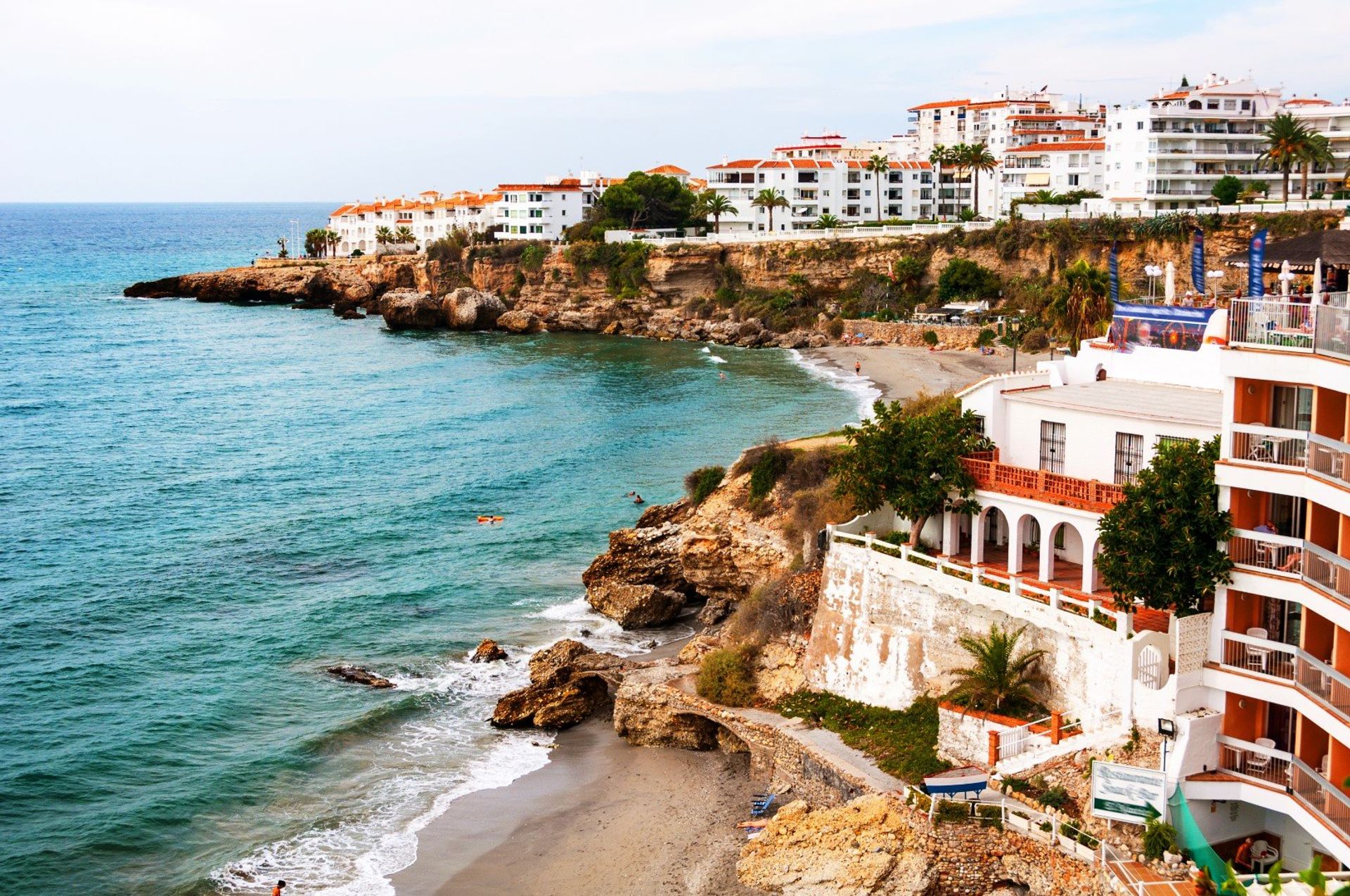 Whitewashed houses on the rocky cliffs of Nerja's beautiful sunny coastline