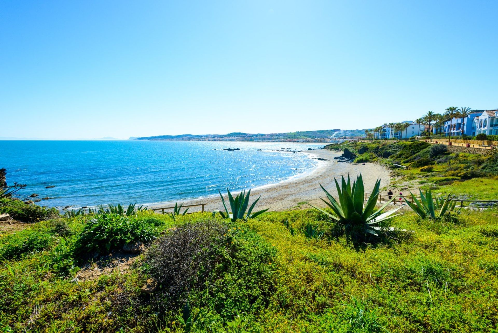 Revel in the lush green landscape on Playa Chica beach while enjoying views of the sparkling Mediterranean
