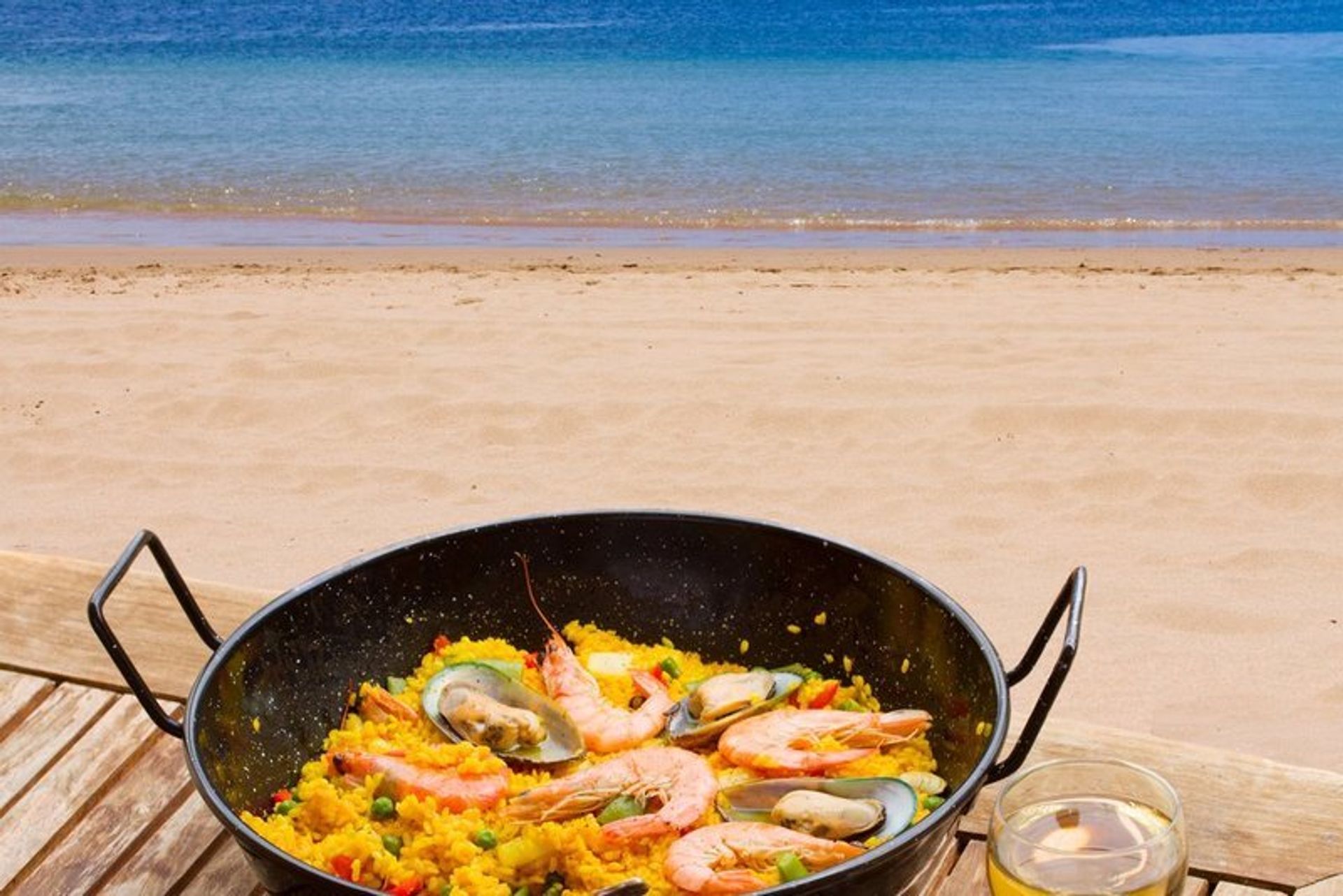 Paella and a glass of wine by the beach - a Valencian classic!