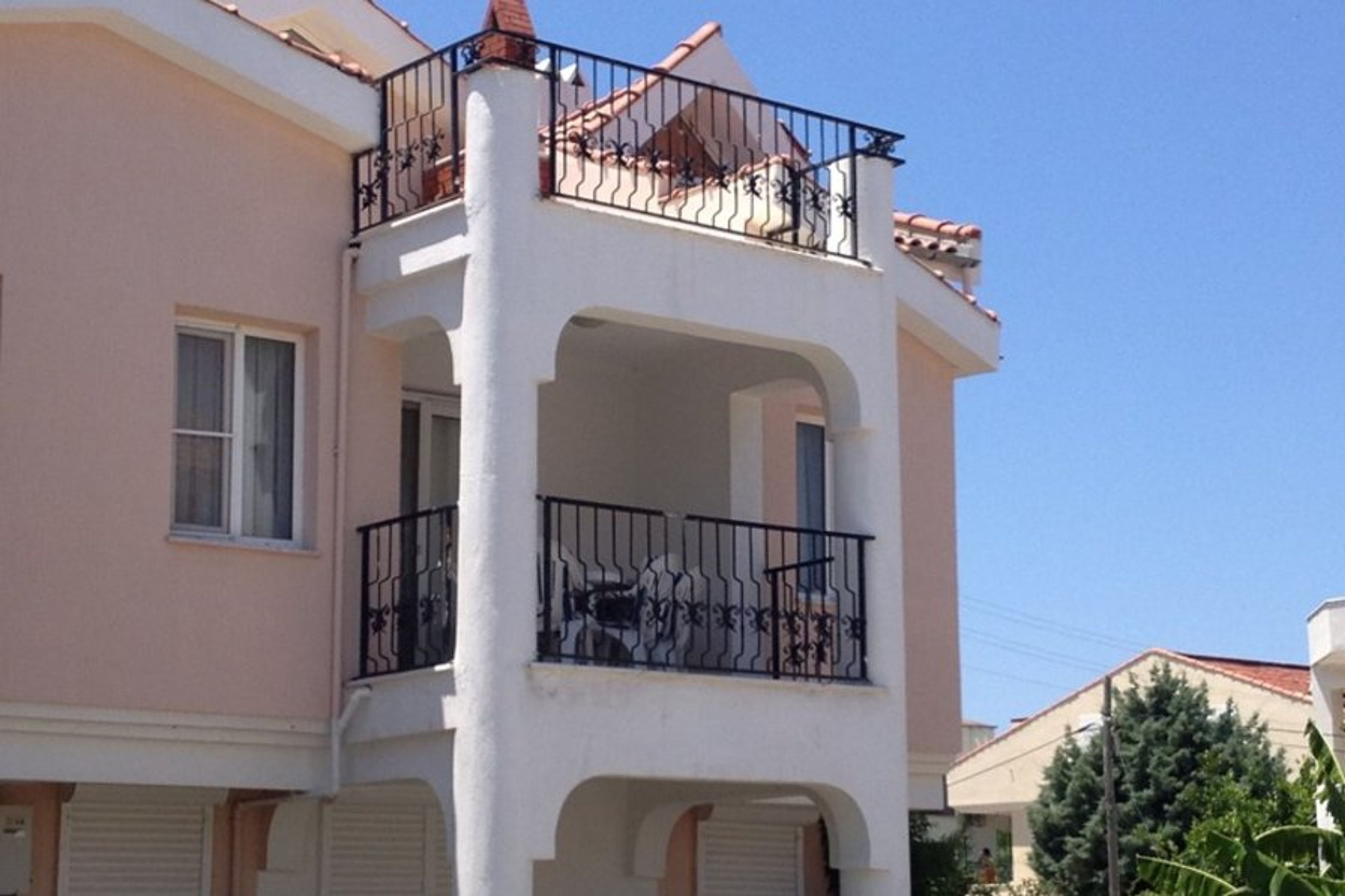 Exterior of apartment, showing lower level shaded balcony, and upper level sun terrace with barbecue and sea view.
