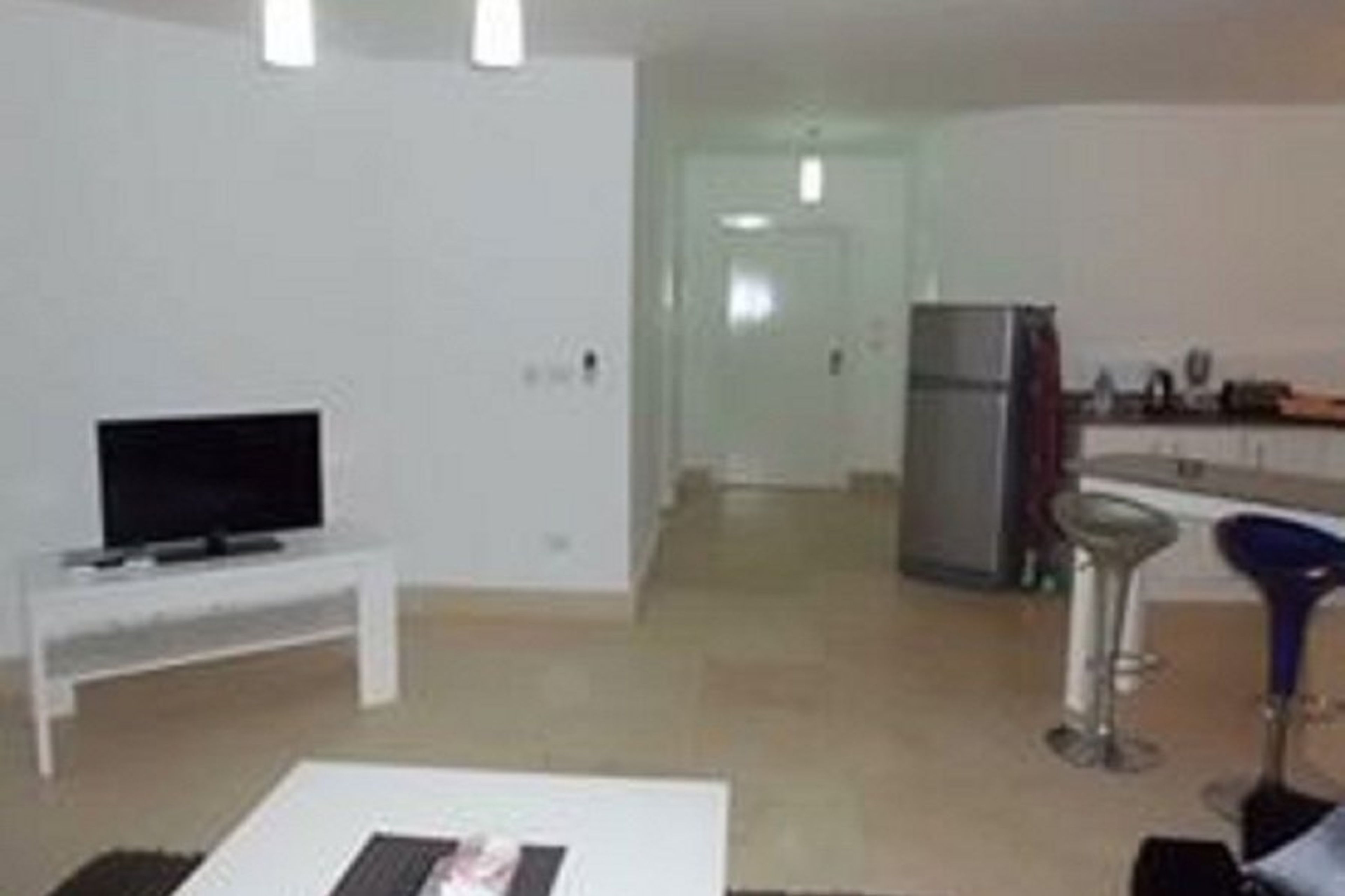 Living area with televisio towards entrance of apartment/kitchen