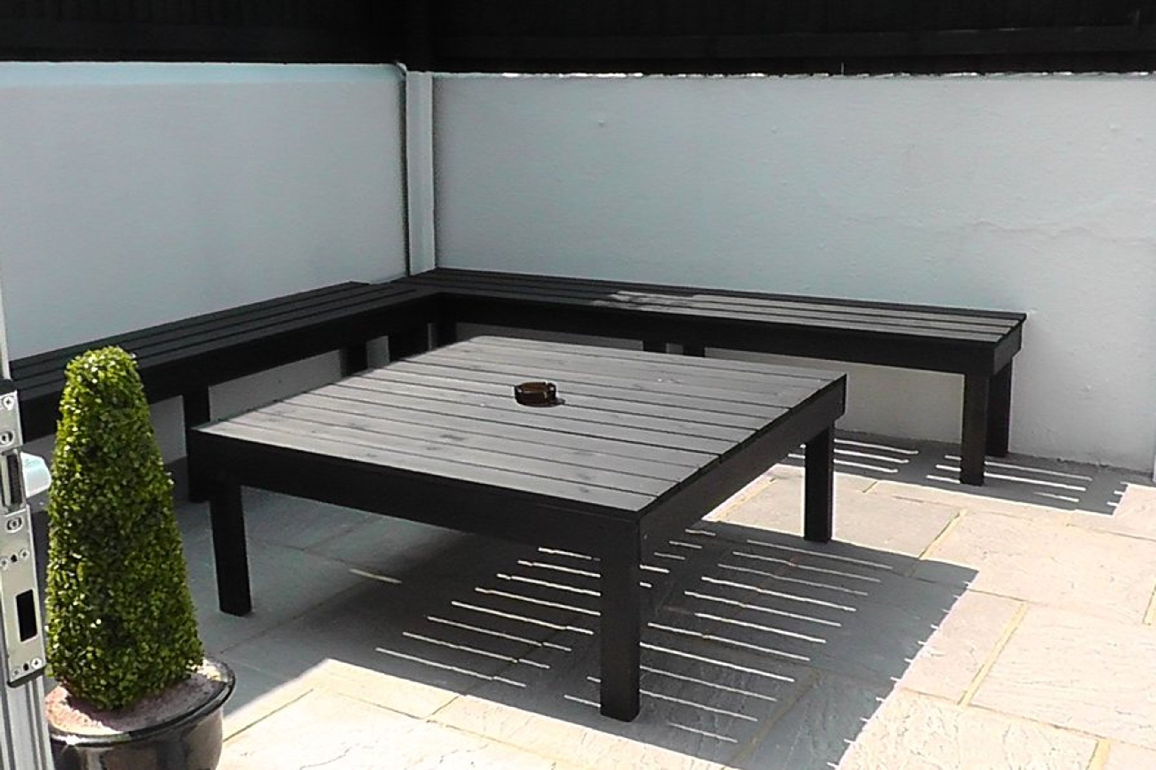 Sunny courtyard garden with seating for 12 on benches.