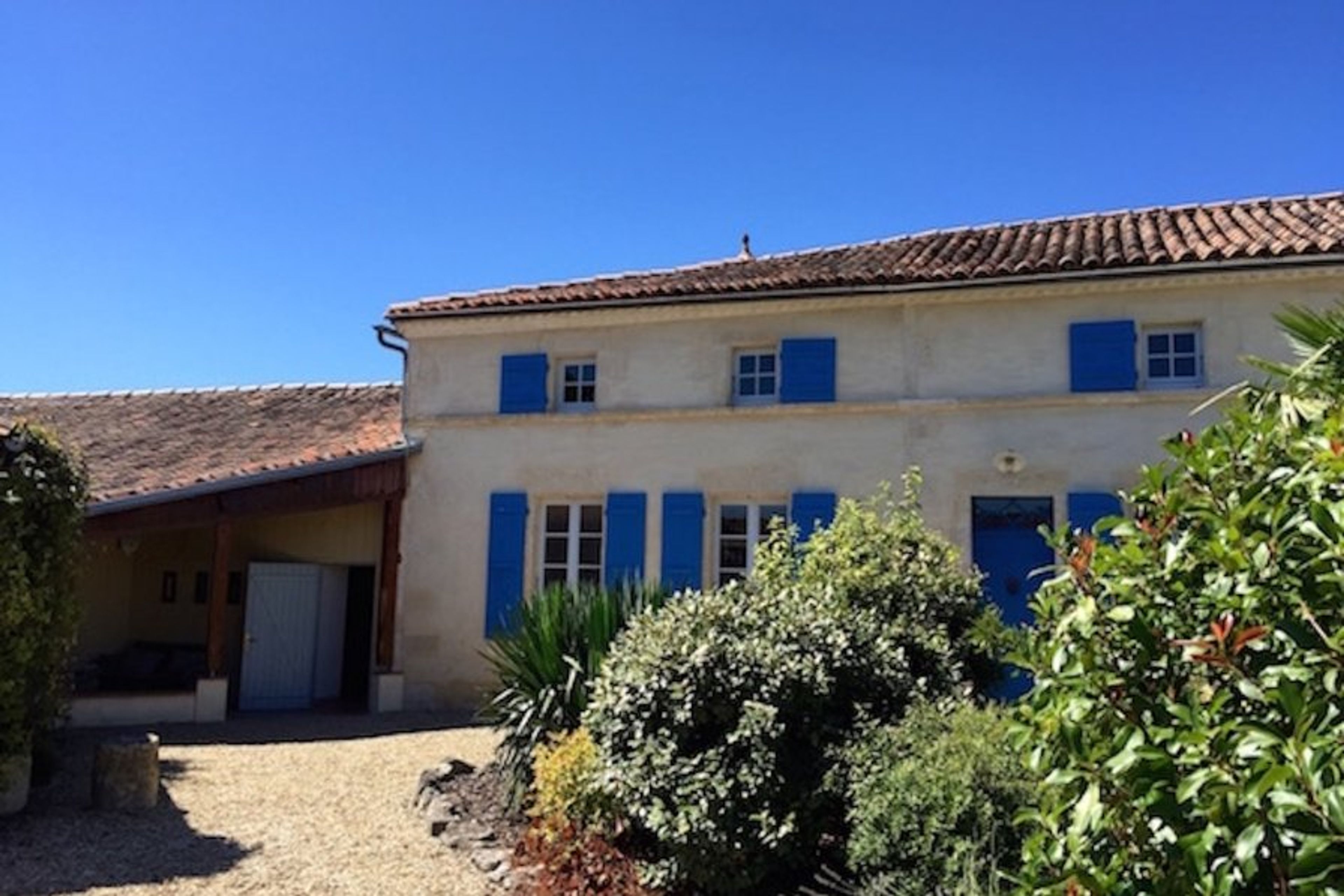 The house is built from buttery Charente stone with blue shutters.