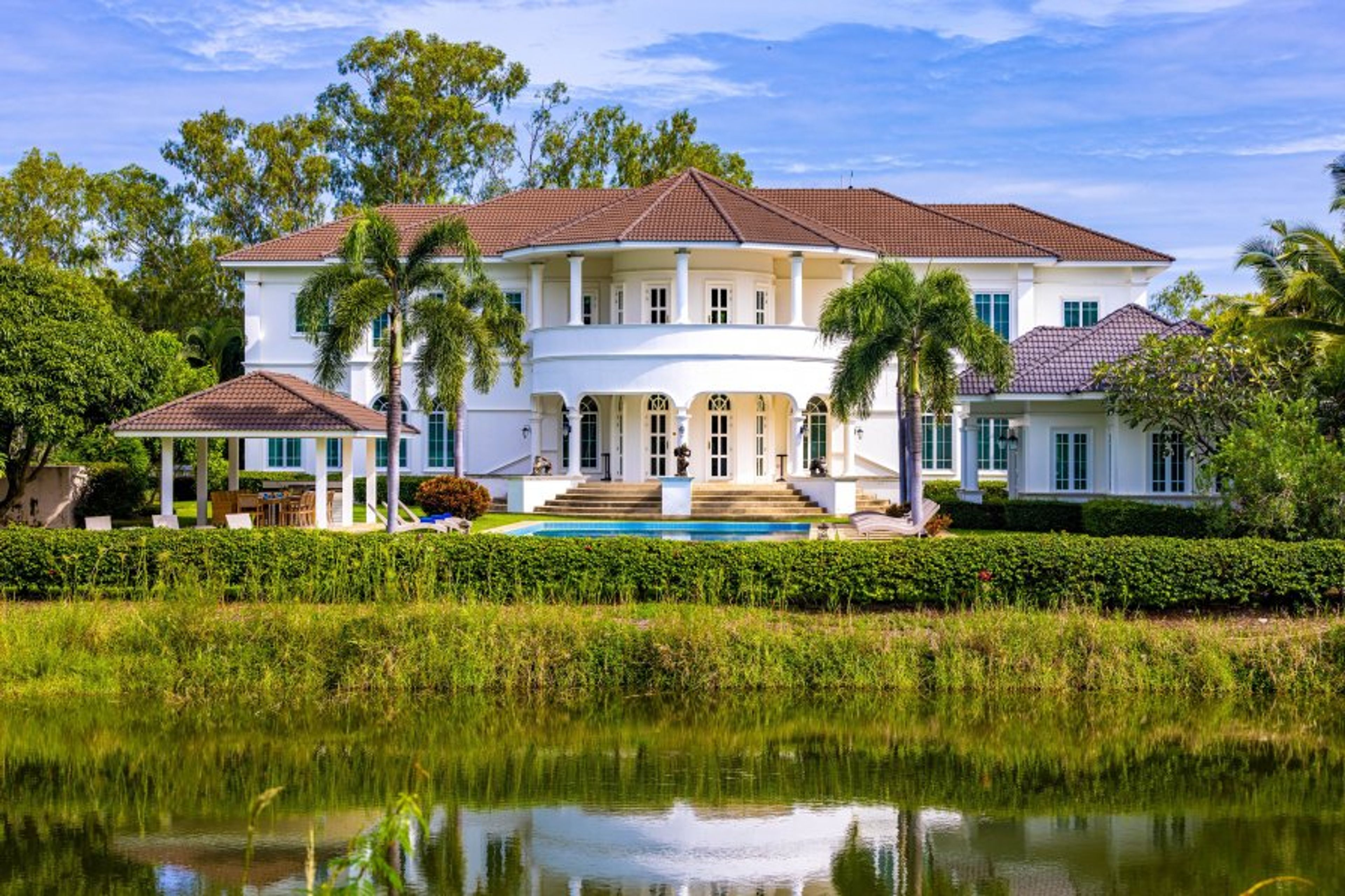 The house, pool, and garden are seen from the Palm Hills golf course.