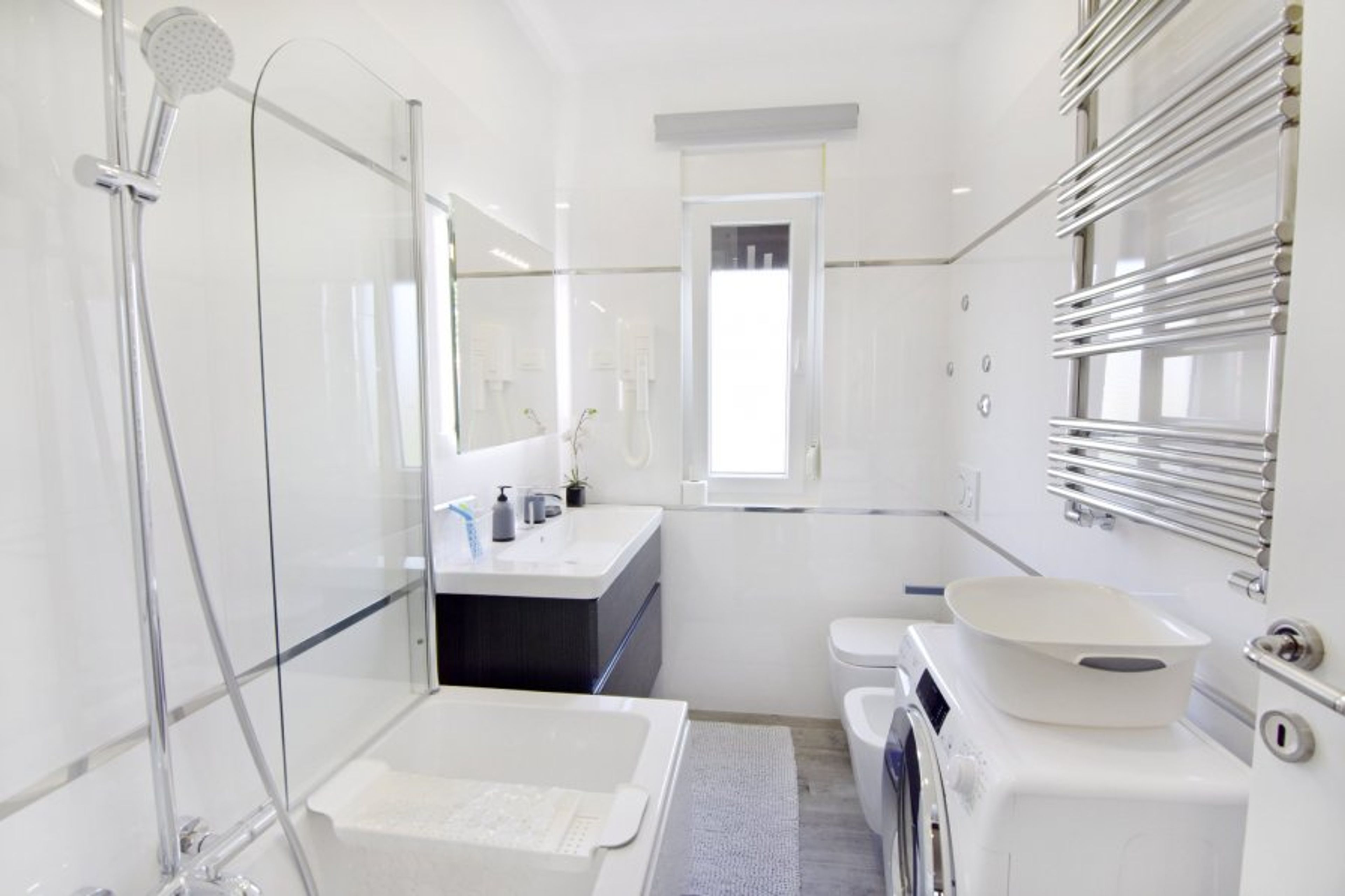 The bathroom with bathtub, sink with cabinet and mirror, bidet, toilet