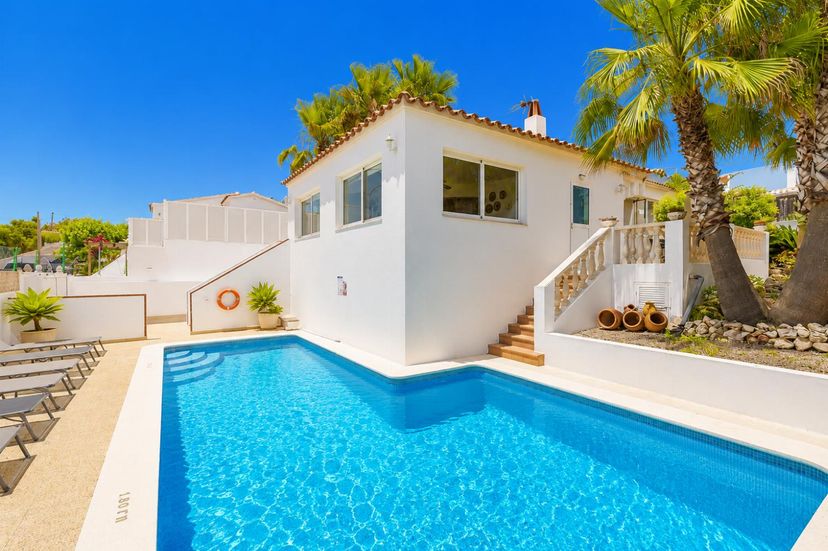 Villa in Spain, Cala'n Porter: White villa featuring a private swimming pool, sun loungers, and tr..