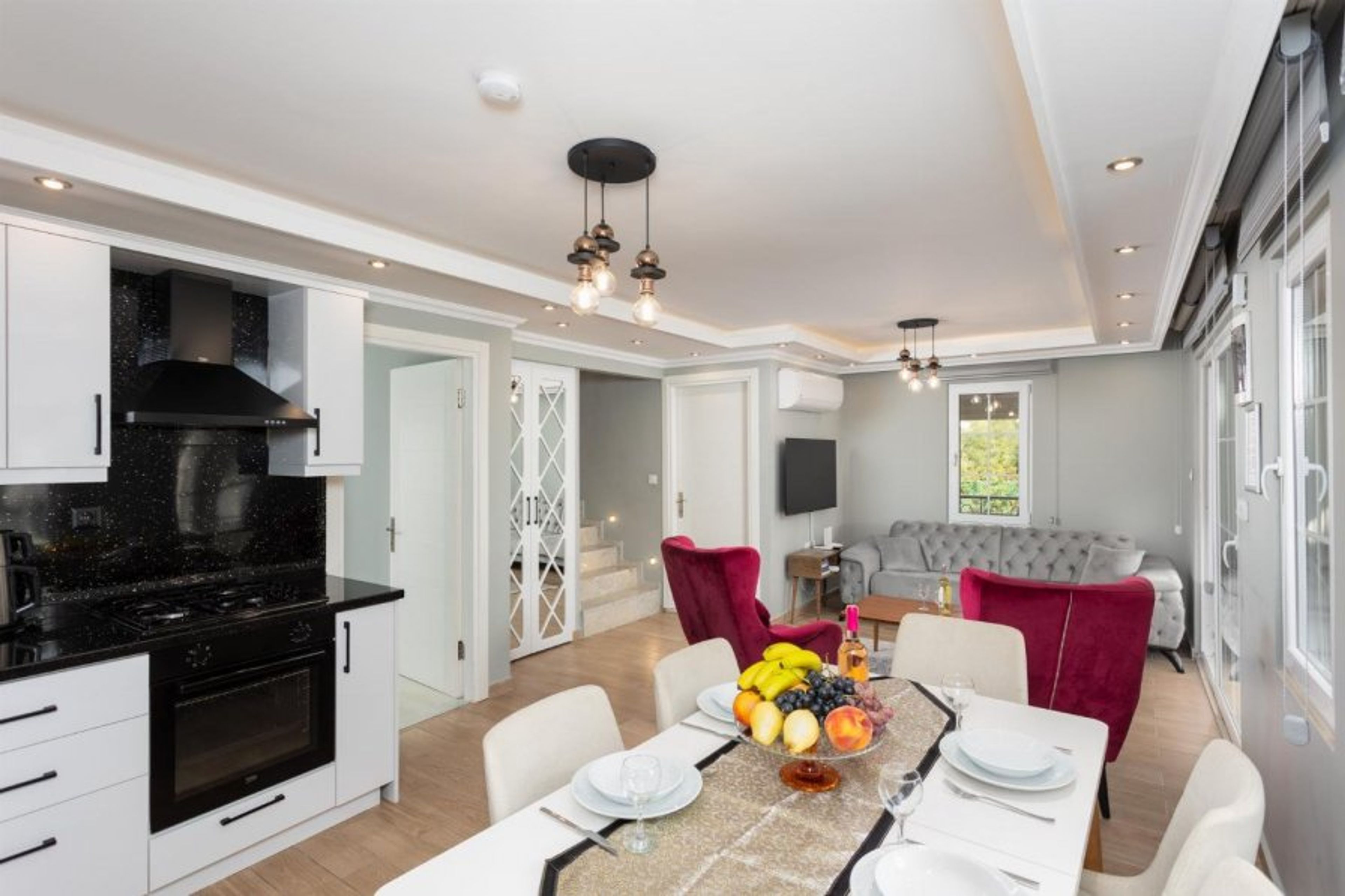 Open-plan living room with sofa, dining area, kitchen, A/C, WiFi internet, and satellite TV