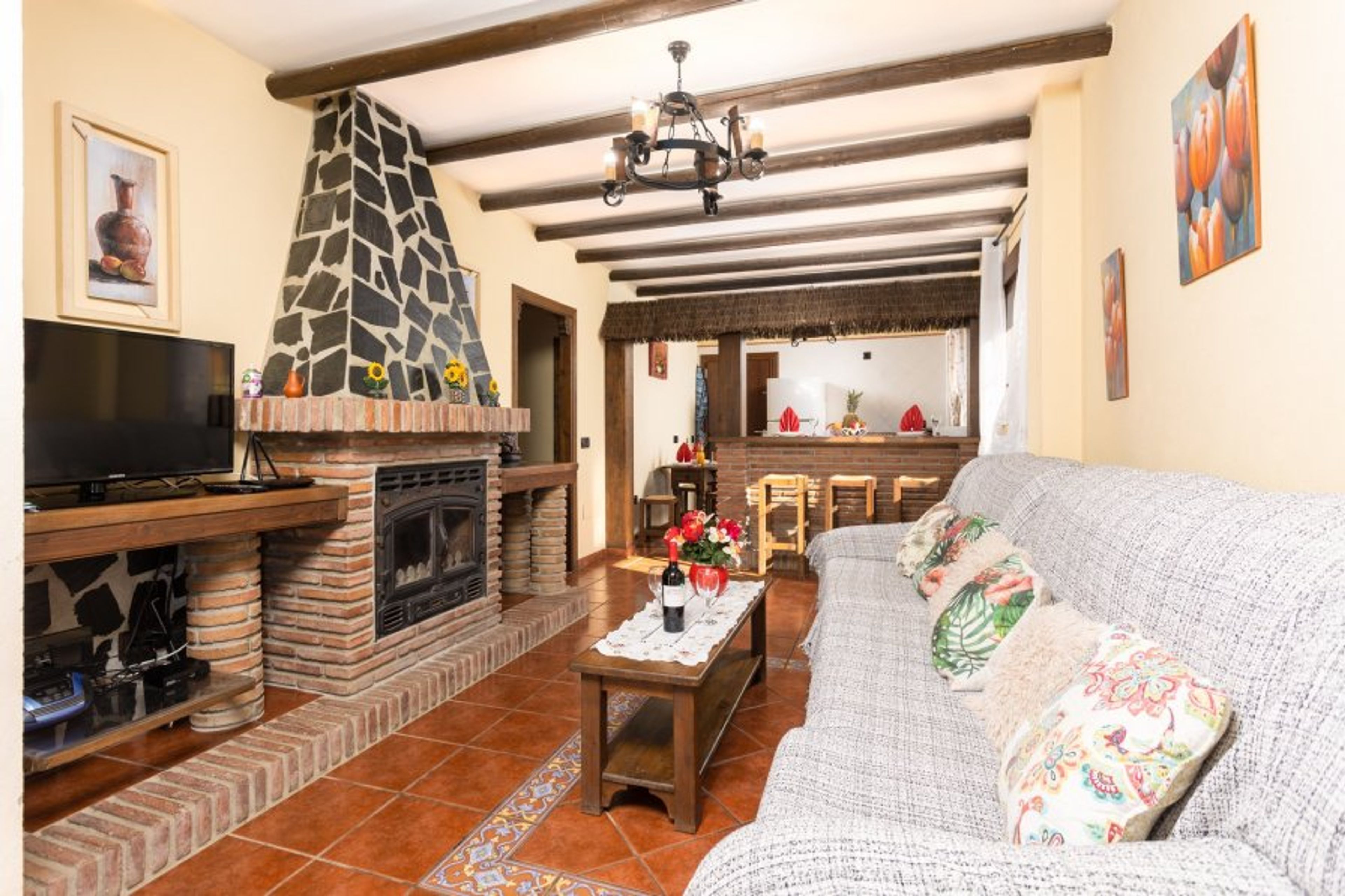 Open-plan living room with sofa, dining area, kitchen, ornamental fireplace, A/C, WiFi internet, and satellite TV