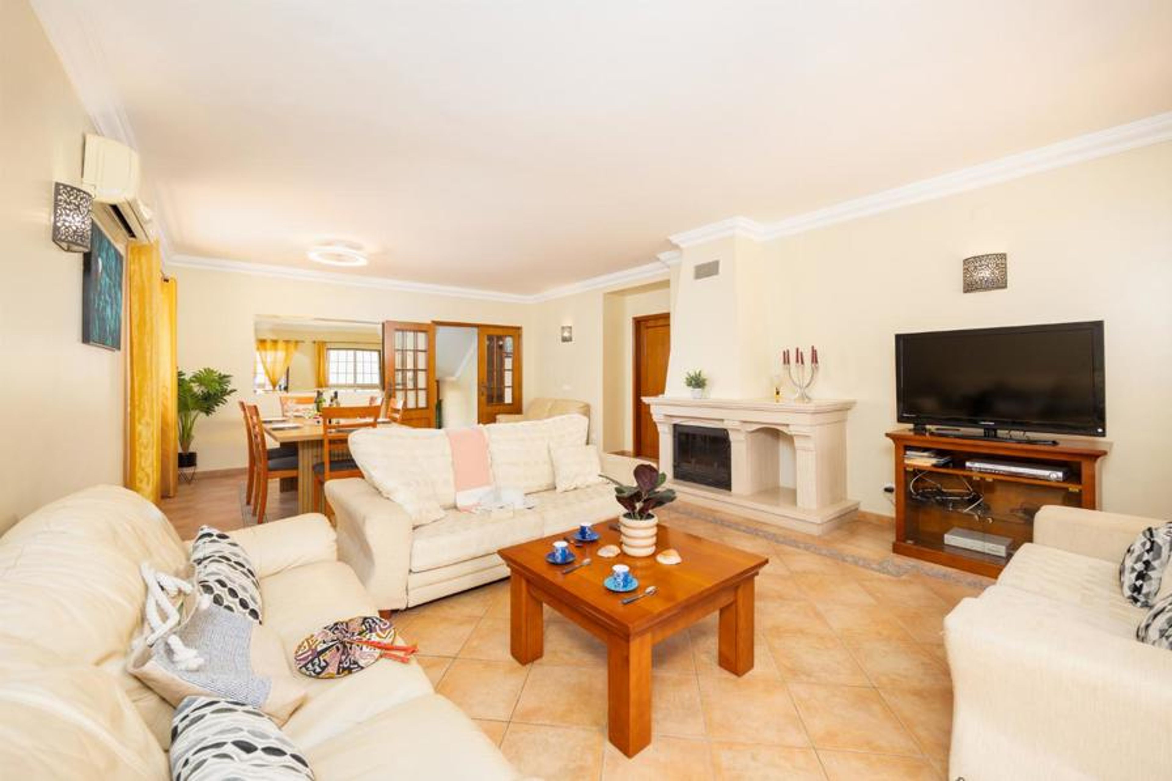 Open-plan living room with sofas, dining area, ornamental fireplace, A/C, WiFi internet, and satellite TV