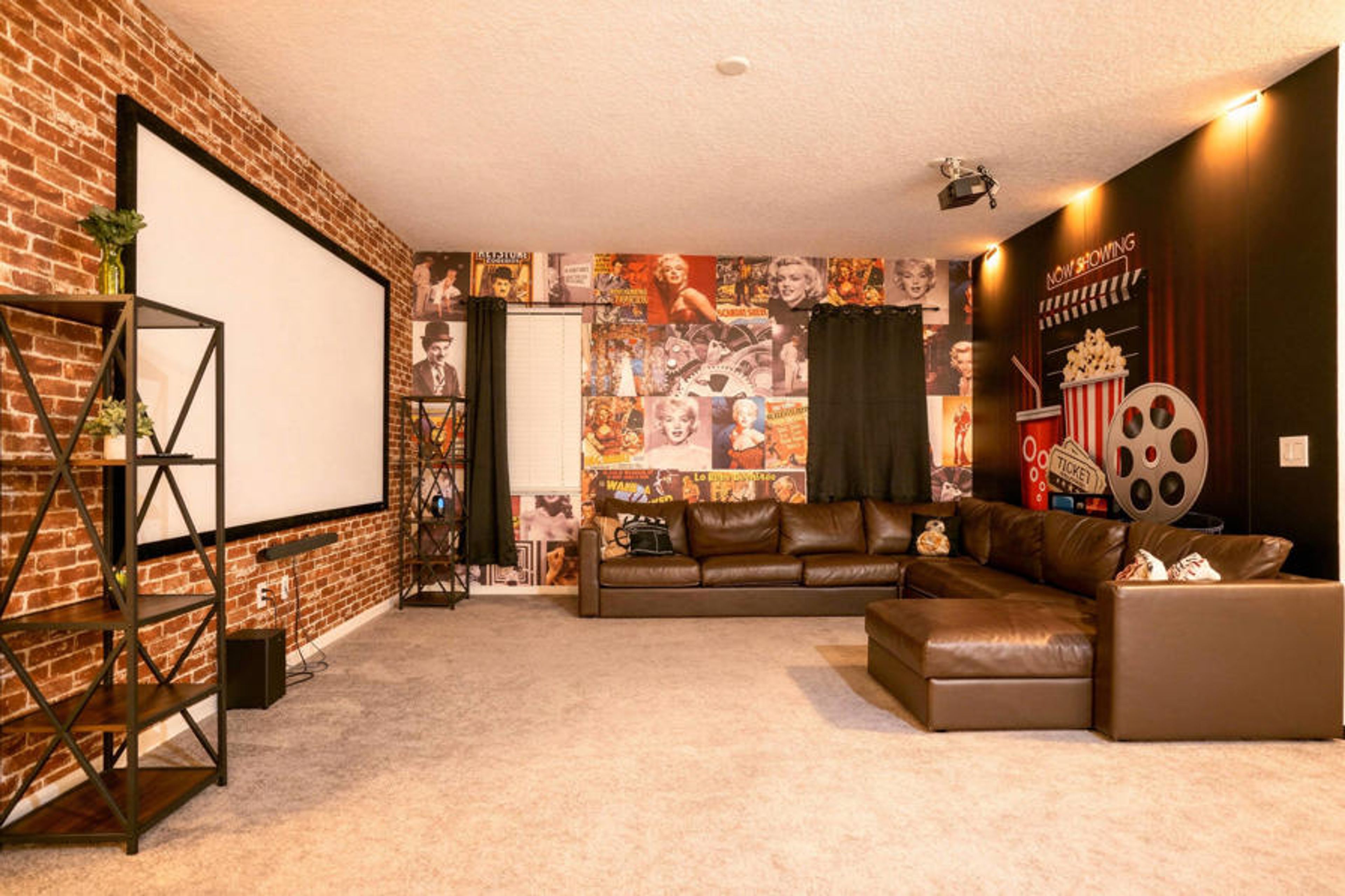 Enjoy a cozy cinema-themed theater room with a large projector screen, plush sectional seating, and warm ambient lighting. Brick accents, vintage movie posters, and playful popcorn decor create the perfect spot for family movie nights.