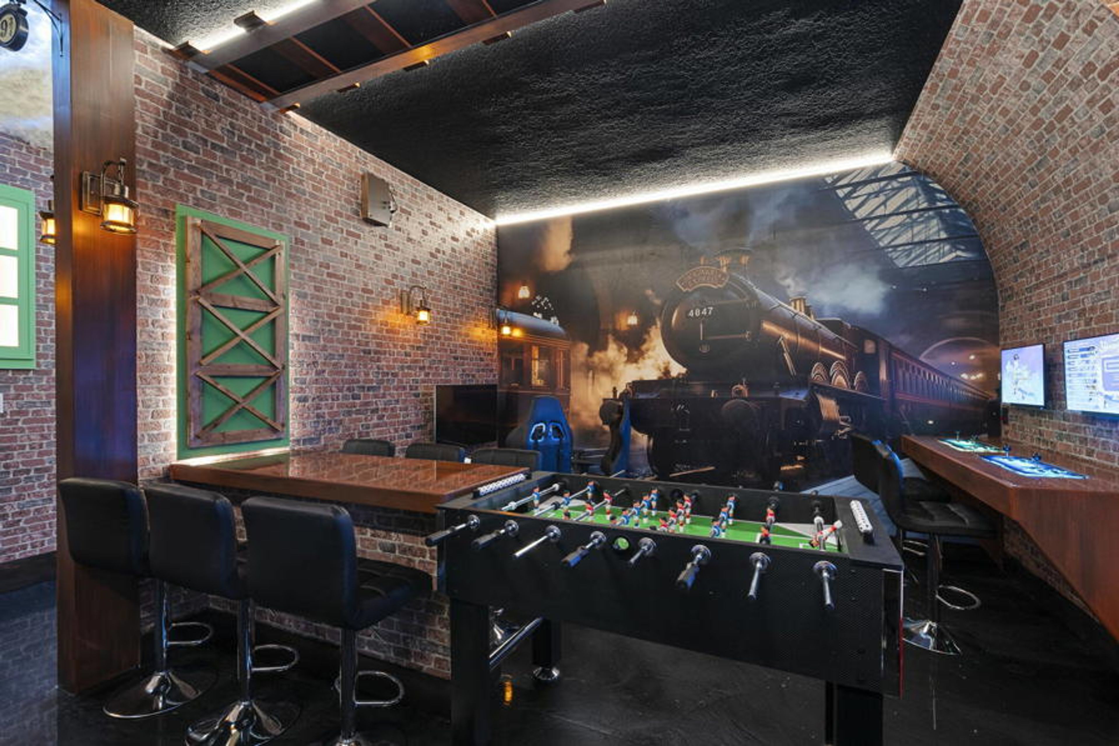 Step into a playful escape, featuring a foosball table and a striking mural of a vintage train, perfect for lively evenings with friends. The exposed brick walls and industrial lighting create a unique blend of comfort and style.