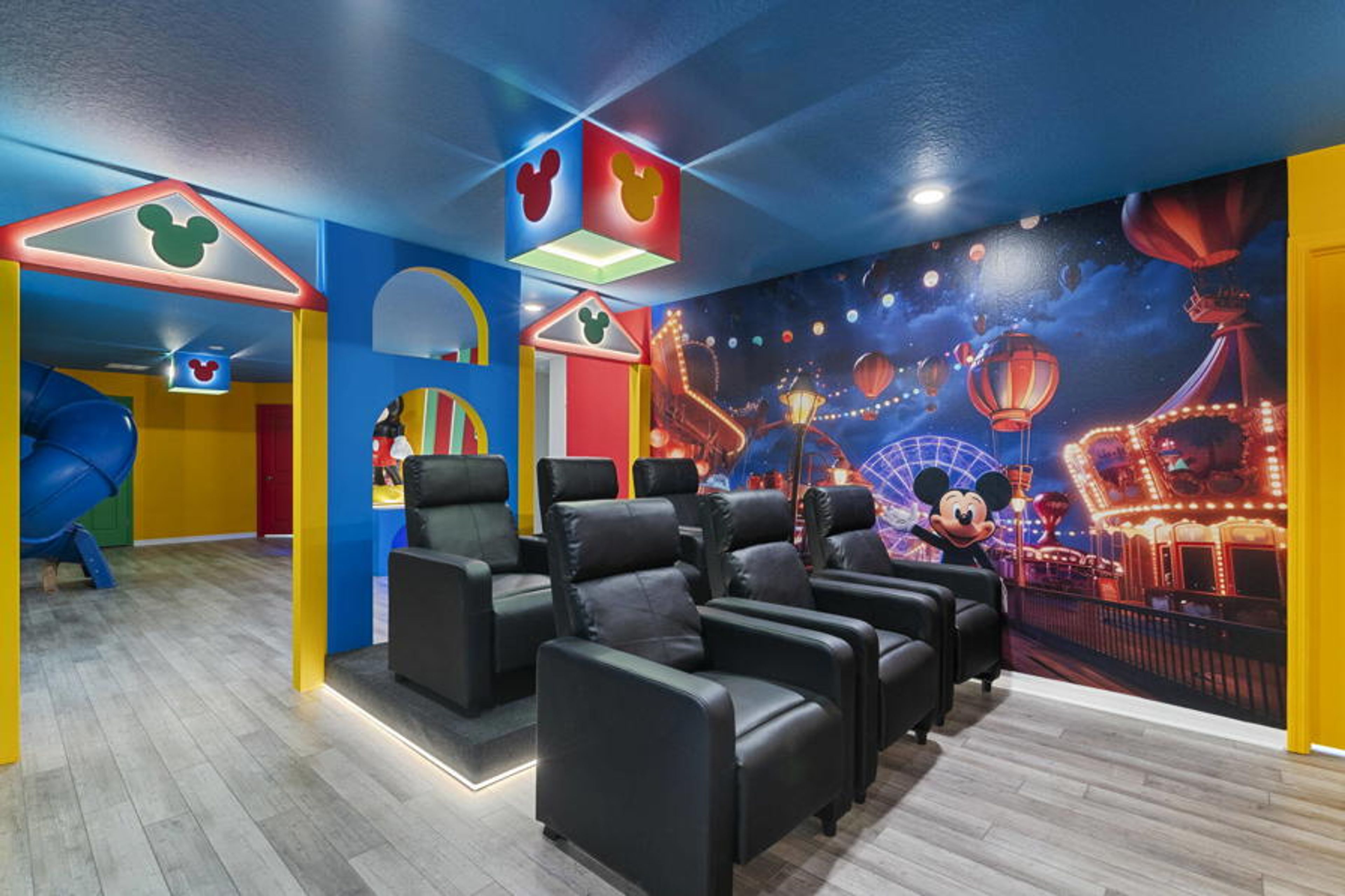 Step into a vibrant entertainment room with plush black reclining seats that invite relaxation. Colorful accents and a whimsical wall mural create a playful atmosphere, perfect for movie nights or enjoying time with loved ones.