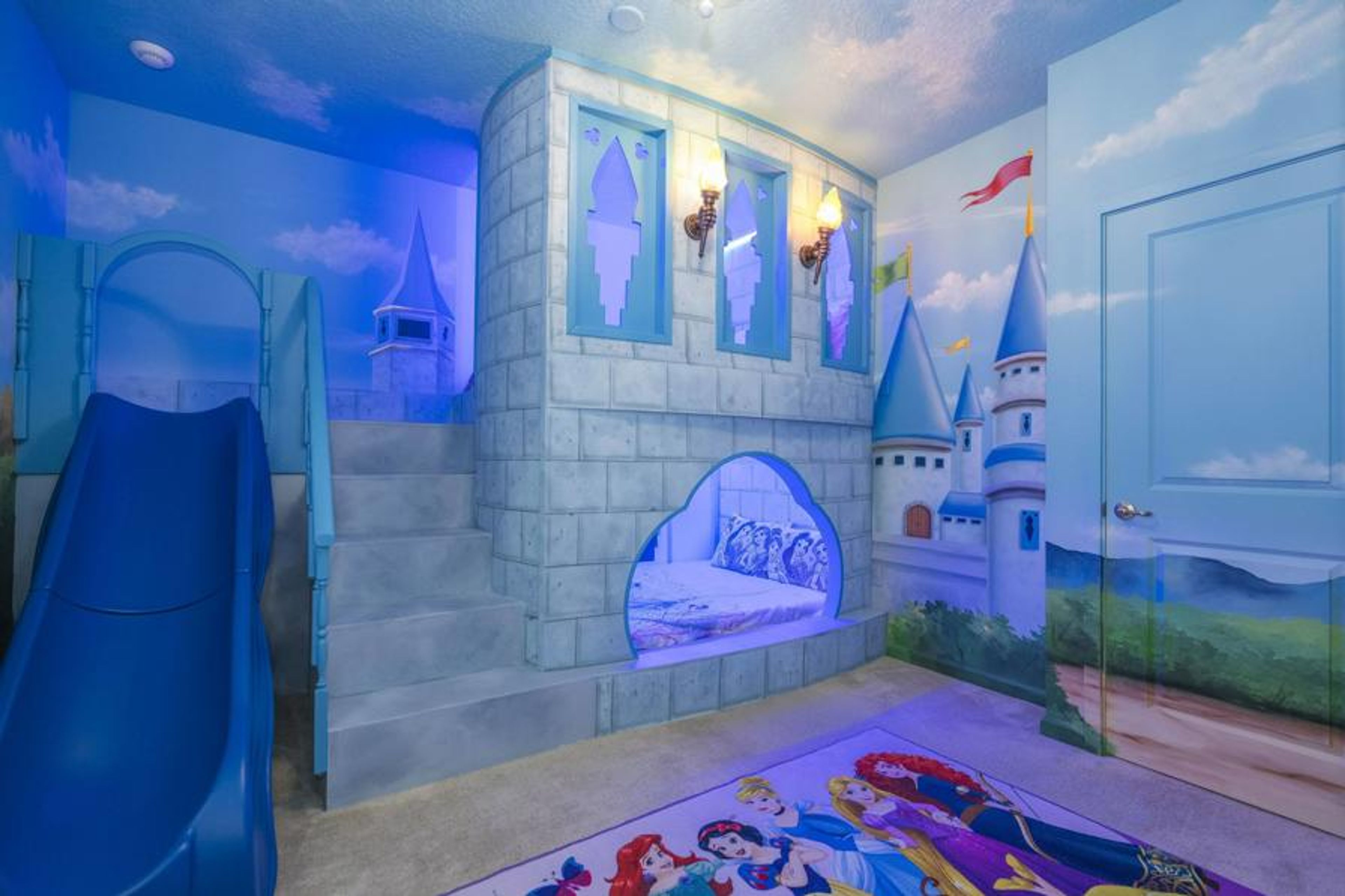 Enter a whimsical playroom filled with vibrant castle murals and a fun slide for adventure. Enjoy the cozy, colorful carpeting and soothing blue lighting that create a magical atmosphere ideal for imaginative play.