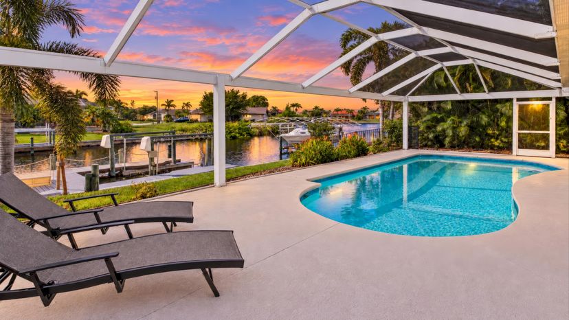 Villa in USA, Cape Coral: Sunset colors frame the screened pool terrace, with loungers and a peace..