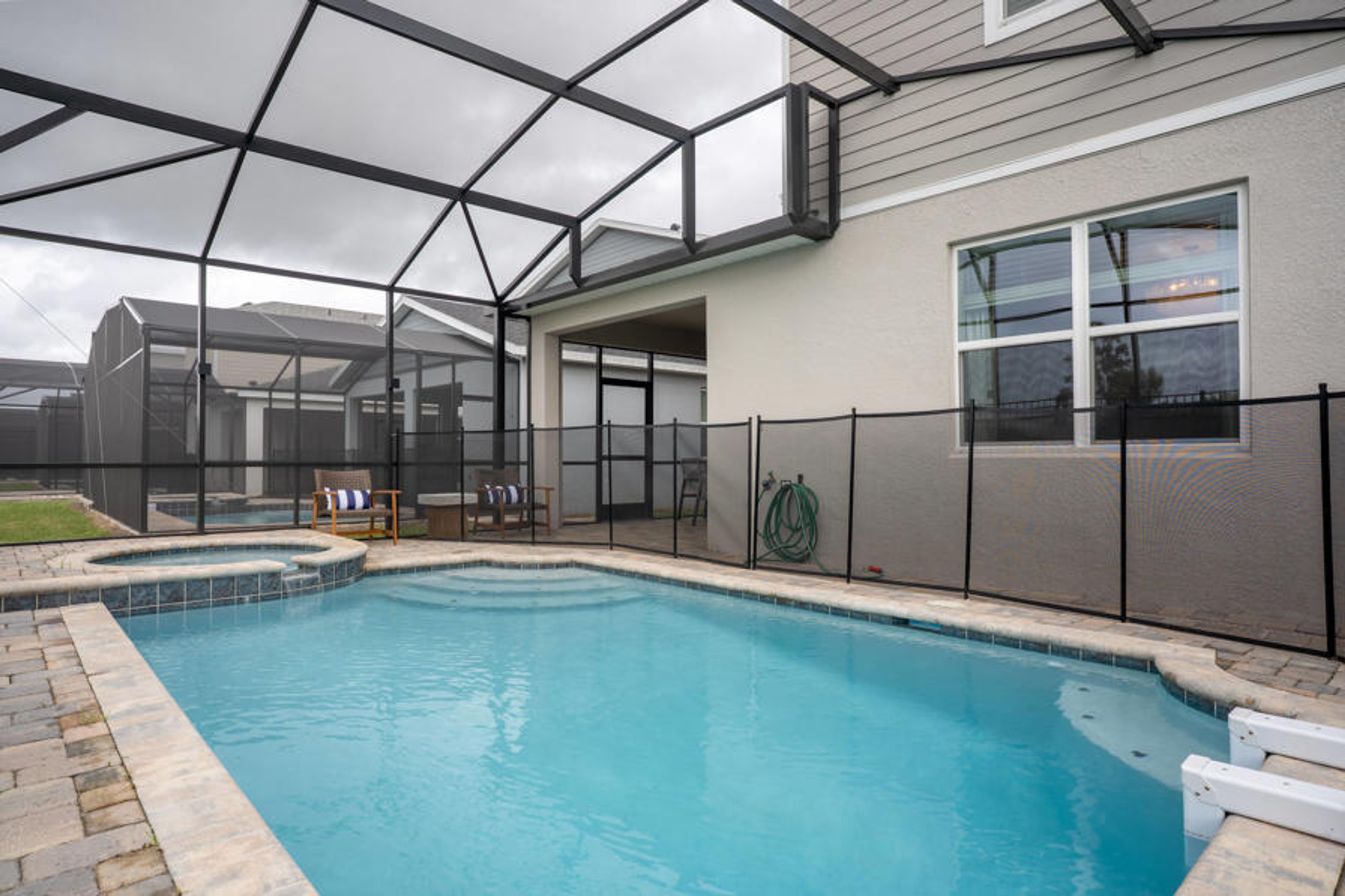 Step outside to discover your private oasis featuring a sparkling pool and stylish screened enclosure. The elegant stone patio invites relaxation, and comfy lounge chairs are perfect for sun-soaked afternoons and serene evenings.