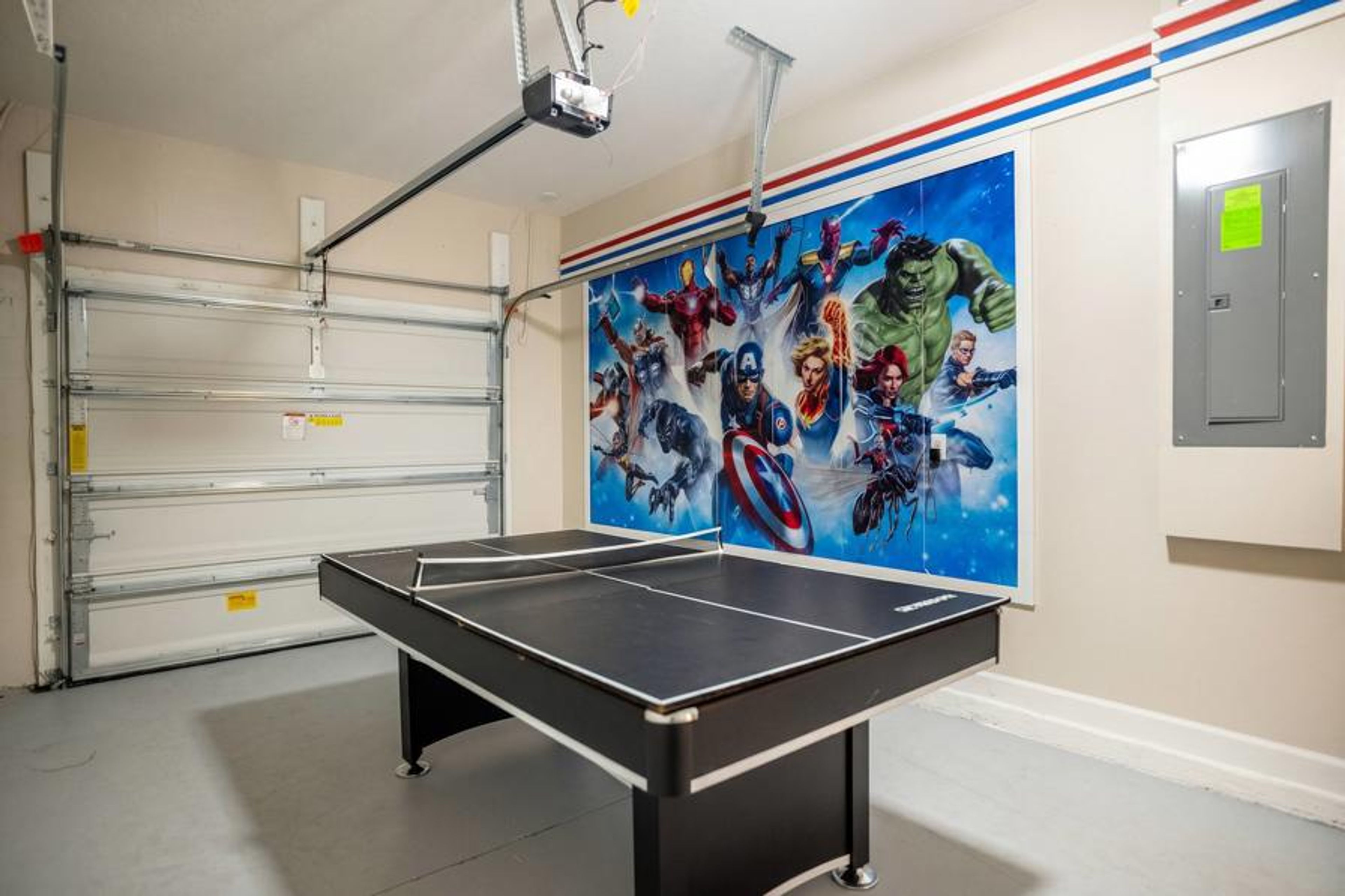 Have fun in a superhero themed game garage with a ping pong table, bold wall art, bright lighting, and open space, creating a great area for family entertainment during vacation.