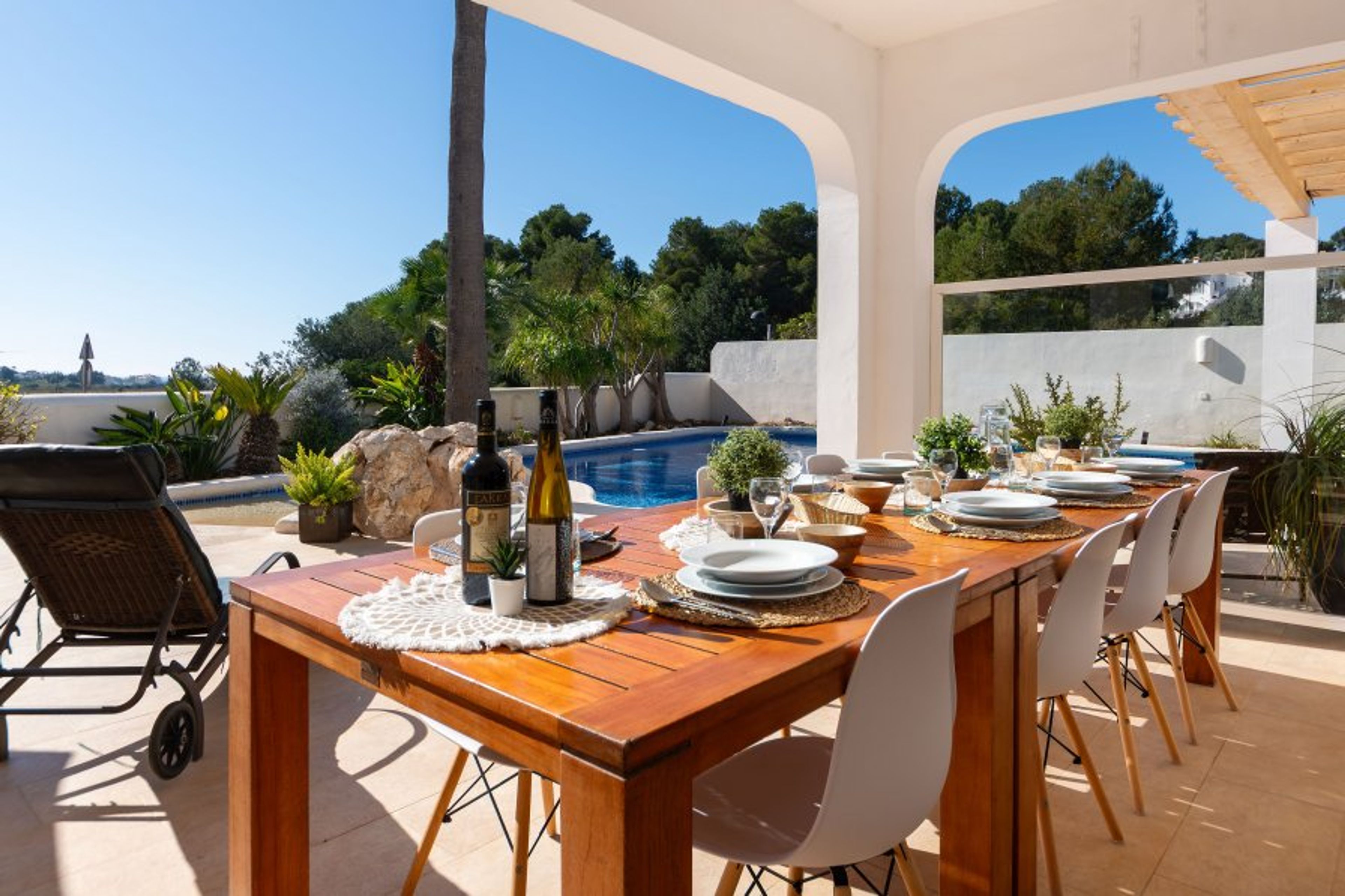 Large dining table under the covered terrace next to the pool