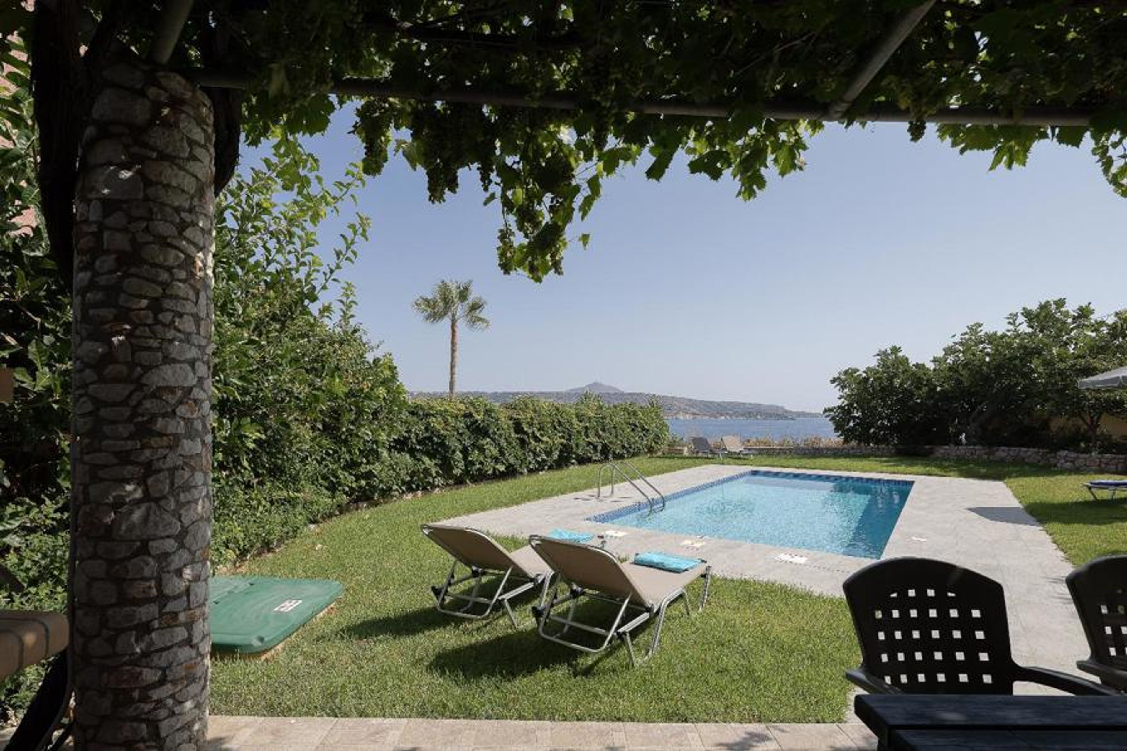 Private swimming pool with sun loungers, shaded terrace, lush Mediterranean gardens, and beautiful panoramic sea views.