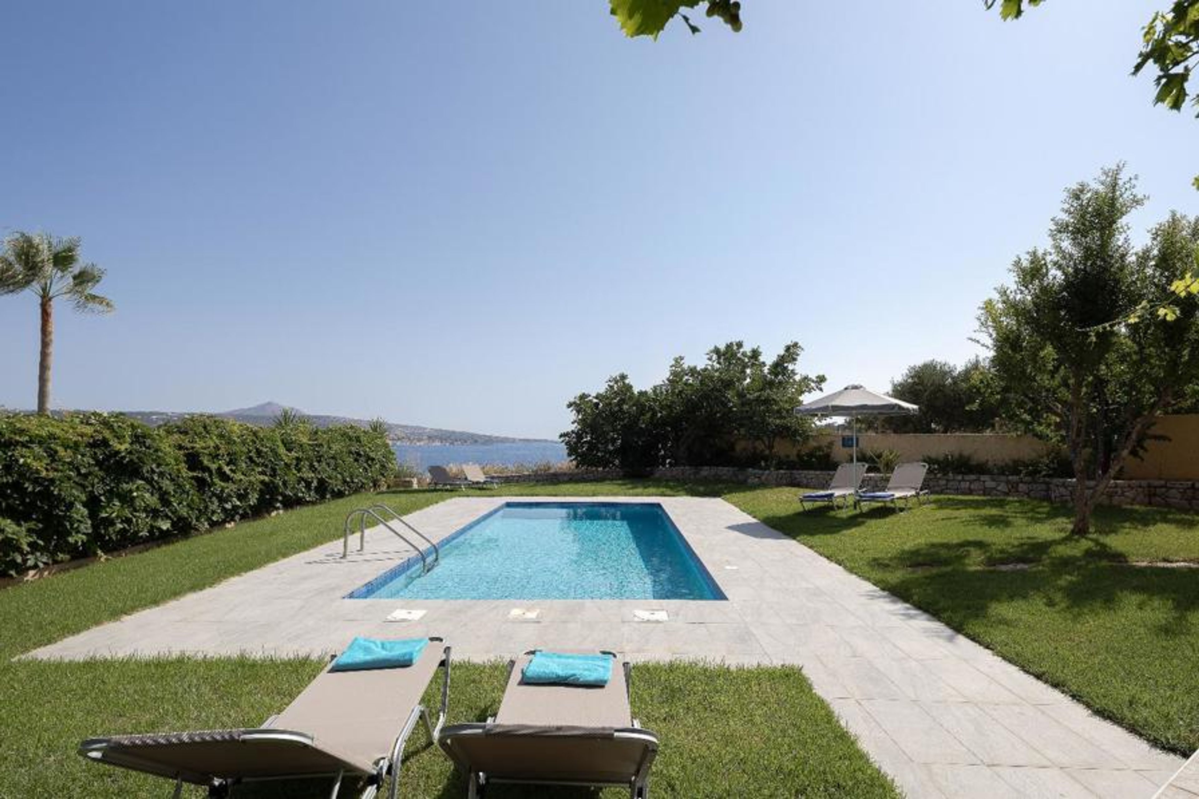 Private swimming pool with sun loungers, spacious lawn, lush Mediterranean gardens, and beautiful sea views.
